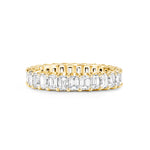 A yellow gold eternity ring featuring a continuous row of emerald-cut clear diamonds on a plain white background.